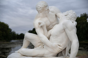 Very old sculpture of a couple of men embracing in white marble