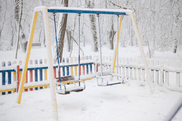 Snow-covered multi-colored fence made of wood. Severe frost, the playground is closed. Snowing