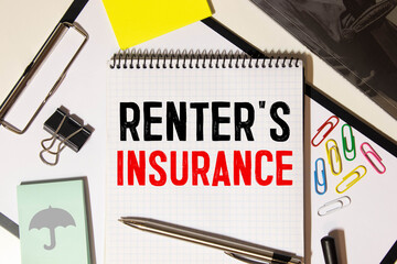Notepad with text Renter's insurance, paper clips, pen,on financial diagrams. Business