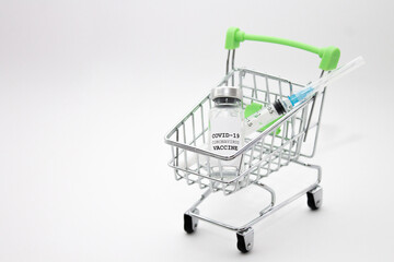 Shopping cart and COVID-19 vaccine bottle with space for text. Buy coronavirus vaccine concept.