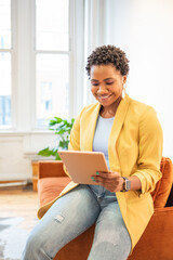 Young woman sitting on a couch and holding a tablet