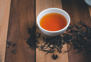 A tea cup with dry tea and wooden background