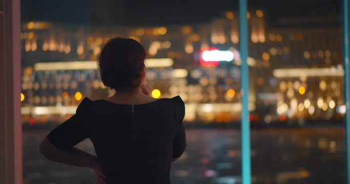Young successful businesswoman standing near window with panoramic city view