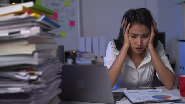 Stressed busy woman with headache working from home late at night on laptop feeling tired and sleepy