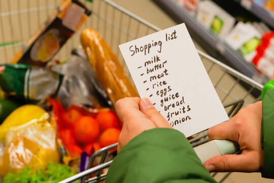 list of products in hands. supermarket with grocery cart.