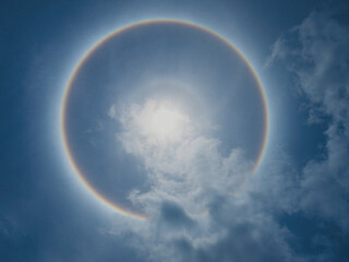 Obraz na płótnie Canvas Solar Halo Also known as a 22-degree halo or a sun halo, with the sun in the center of ring is caused by sunlight passing through ice crystals in cirrus clouds within the Earth's atmosphere.