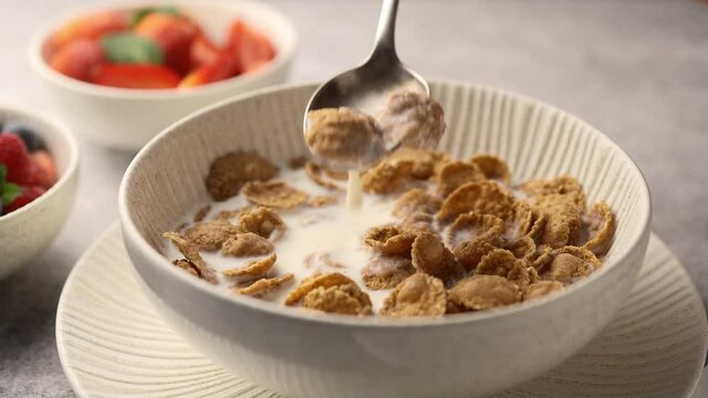 Girl takes multi-grain cereal from a bowl with a spoon, breakfast, close-up 