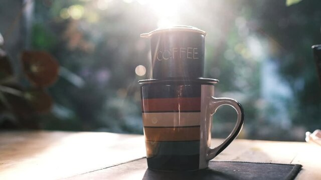 New day with a coffee in the garden. Royalty high-quality free stock footage of a cup of coffee with sunshine, sun flare. Wonderful garden with greenery and fresh air for relaxation. Amazing morning