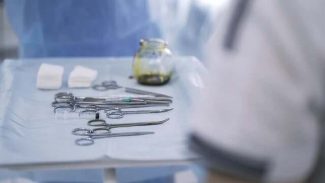 Close up of surgical table with instruments. Action. Medical sterile tools lying on a table with an iodine bowl, concept of medicine.