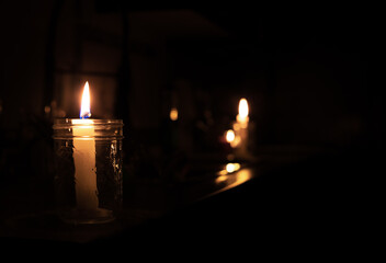 Candles on kitchen counter during power outage. 2 candles are inside a mason jar. Pitch black room...