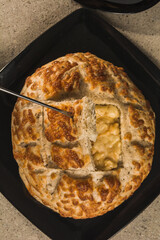 Grain bread, cut in the center to put the fondue cheese, on black plates and a quarry background. 5