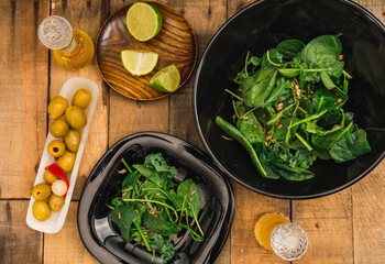 Arugula salad with kale, spinach and sunflower seed accompanied by stuffed green olives,  olive oil on a background of wooden boards. 