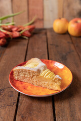 frisch gebackener Kuchen mit eingeschnittenen Äpfeln in Vierteln aus einer Springform zur Jahreszeit Frühling auf einem braunen Tisch aus Holz in der Küche