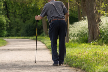 Frail Man Walking With Difficulty With Walking Sticks