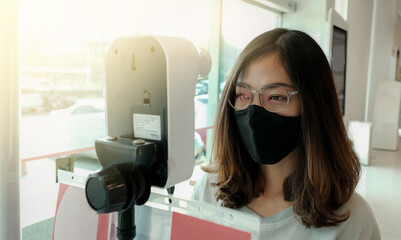 The Asian tourist woman has checked body temperature with a thermal Temperature scanner detector...