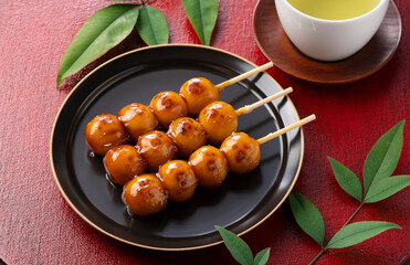 Mitarashi dango and green tea on a red Japanese tray