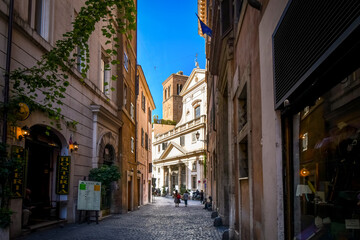 Day view of a shaded alley and the Church of Sant' Eustachio with the head of a white stag holding it's cross in historic Rome, Italy.