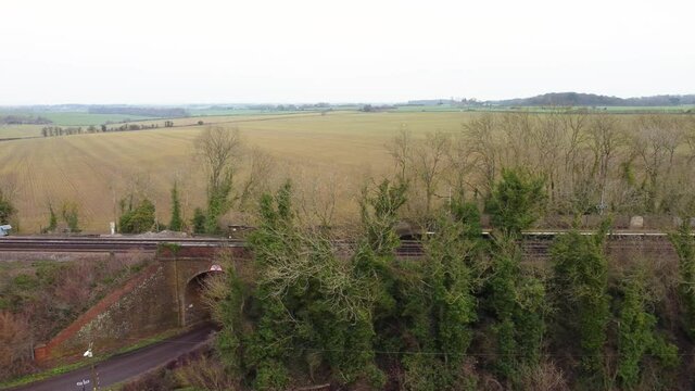 Drone footage of a fly pass of a train track in Kent countryside with railway track bridge.