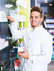 Portrait of glad man druggist in white coat working in drugstore