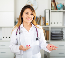 Young mexican female medic in uniform standing in doctor's office