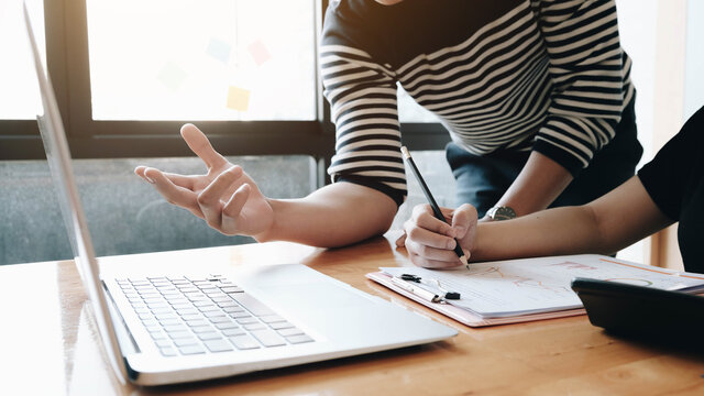 Close up of diverse businesspeople working on project startup presentation in team, comparing statistic data, studying values on graph diagrams, analyzing trends patterns, making notes on paper sheets