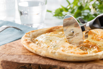 Foto einer Pizza, die mit einem Pizzaschneider geschnitten wird