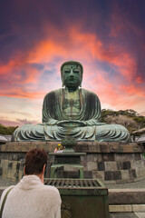 Woman prays at the Great Buddha at Kamakura, Japan