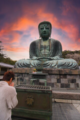 Woman prays at the Great Buddha at Kamakura, Japan