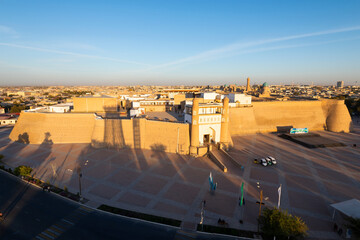 Fototapeta premium Bukhara Fortress (Ark), Uzbekistan in sunset light showing the old city wall, Po-i-Kalan (Poi Kalon) architectural complex and Kalyan minaret.