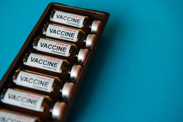 Bottles of vaccine to fight the coronavirus pandemic. Victory over Sars-cov-2 / COVID-19. Some ampoules with vaccine in a box on blue background with copy space.