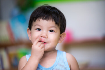 Close-up. An Asian boy uses his hand to eat food in his mouth. Concept of health care, disease...