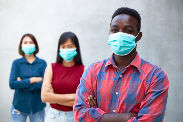 An ethnic group of people wearing anti-virus masks, standing with their arms crossed.