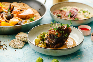 Lamb meat on the bone in sauce and brussels sprouts on the blue background