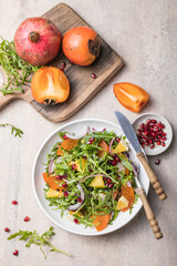 Delicious persimmon salad with arugula  and orange served on light grey table, flat lay. Space for text