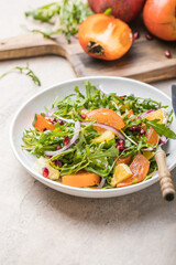 Delicious persimmon salad with arugula  and orange served on light grey table, flat lay. Space for text