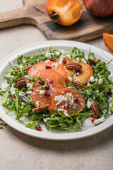 Persimmon salad with arugula, nuts, goat cheese, pomegranate. Healthy vegetarian food concept.