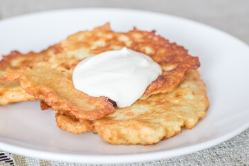 Polish potato pancakes served with sour cream. Polish traditional placki ziemniaczane on white plate.