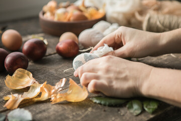 Eco decor. Easter eggs boiled in onions peels. Spring festive easter autentic background. Female hand  holds an egg on a wooden table close-up.