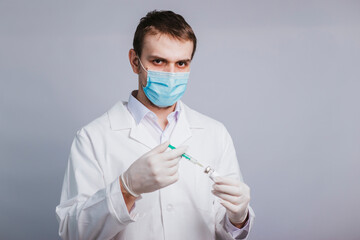 A male doctor in a white coat is taking medicine into a syringe from an ampule. Vaccination and immunization of the population. studio