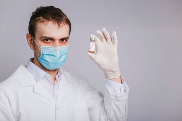 The doctor holds an ampoule of covid-19 vaccine. Vaccination and immunization of the population against coronavirus.