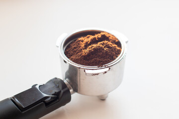 Coffee holder with ground coffee on white background.