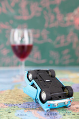 The overturned car model and a glass of wine in the distance