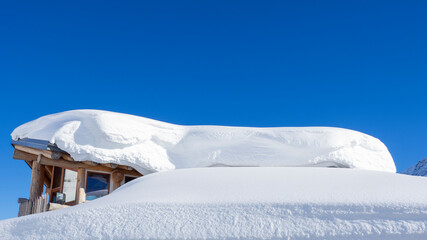 The roof of an house or hotel covered by massive quantity of fresh snow after heavy snowfall. Mountain and winter contest. Italian alps