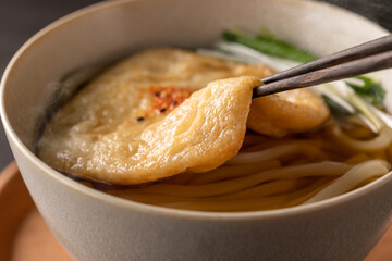 箸ですくった、温かいきつねうどん