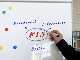 Concept about MIS Management Information System . Hand holding a marker pen to writeon the white board. © Yurii Kibalnik
