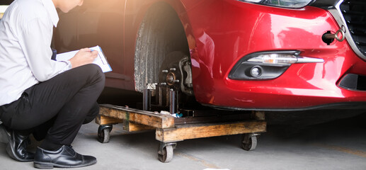 Asian saleman inspector checking writing on clipboard change wheels in garage of dealership mechanic In showroom car and insurance for check to travel to happy new year 2021
