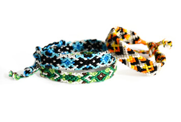 Fototapeta premium Selective focus of tied woven friendship bracelets with bright colorful patterns handmade of thread isolated on white background
