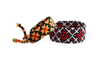 Selective focus of tied woven friendship bracelets with bright colorful patterns handmade of thread isolated on white background