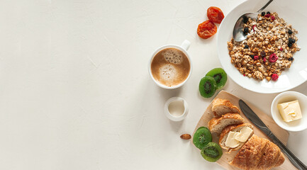 Winter breakfast with croissant, granola and dried fruit on a light grey table. Healthy breakfast.