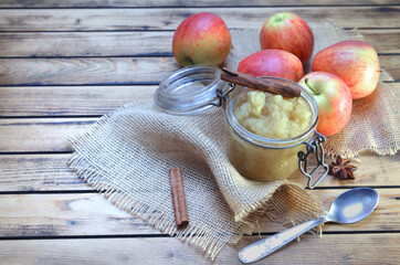 homemade compote in a glass jar with red apples  and cinnamon on a wooden table
